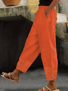 Damenhose in leuchtendem Orange, lässiger Stil mit Knöpfen und floralen Details. Perfekt für Sommermode und Freizeitoutfits.