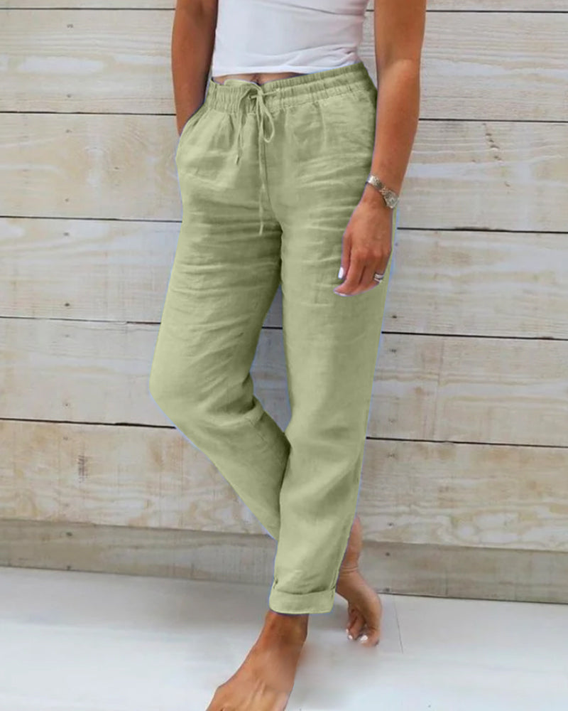 Frau trägt grüne Leinenhose, lässig, mit Taschen, vor Holzwand.