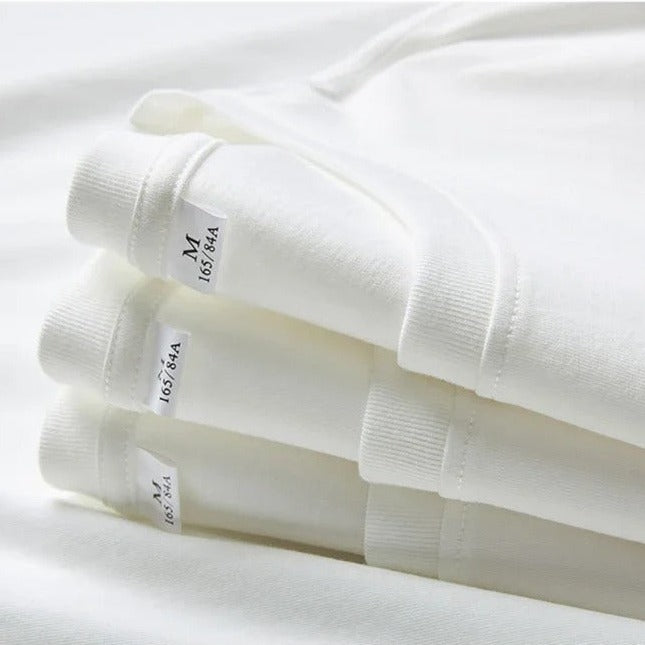 Vier weiße, gefaltete T-Shirts aus Baumwolle, Größe M, aufeinander gestapelt. Hochwertige Basics, ideal für Herrenmode und Freizeitkleidung.