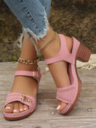 Rosa Sandalen mit Blockabsatz, perforiertem Design und goldener Schnalle, kombiniert mit zerrissenen Jeans. Perfekt für Sommermode und Freizeitlook.