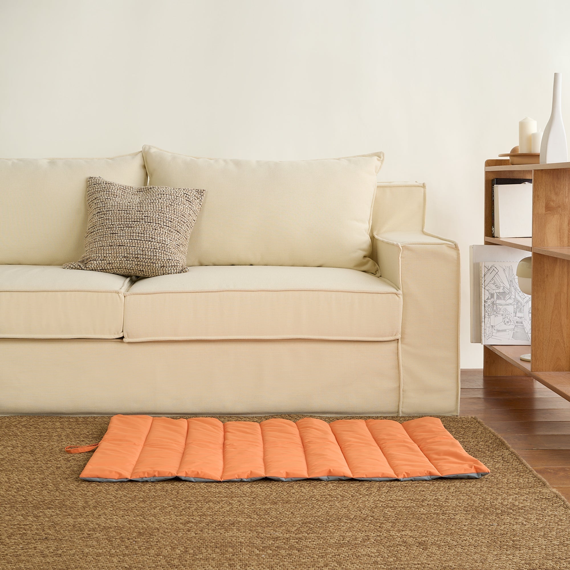 Wasserfeste orange Haustiermatte auf Teppich vor beigem Sofa im Wohnzimmer.