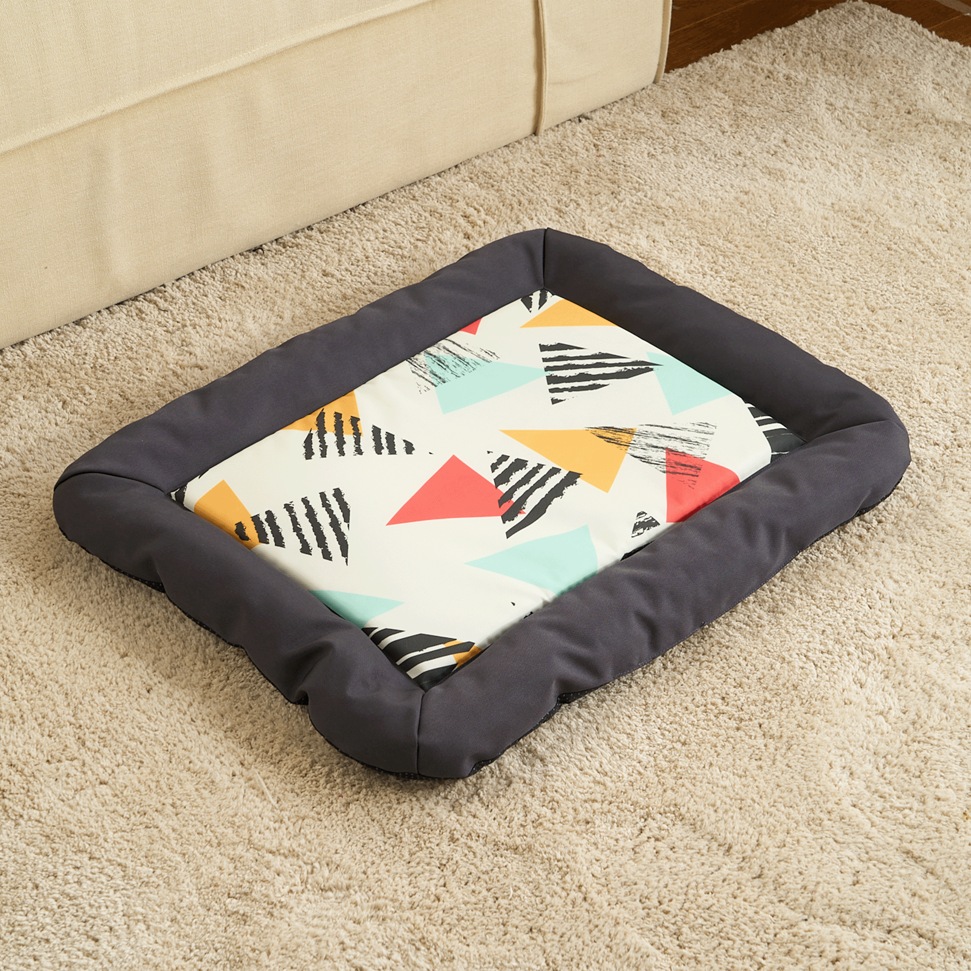Buntes Hundebett mit geometrischem Muster, rechteckig, weiche Ränder, auf Teppich.