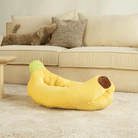 Gelbes Bananen-Sofa-Haustierbett auf beigem Teppich vor cremefarbenem Sofa.