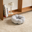 Graues Katzenbett aus Plüsch auf Teppich, rundes Design, gemütlich, ideal für Haustiere.