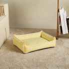 Gelbes kariertes Hundebett, abnehmbar, gemütlich, auf Teppichboden, modernes Design.
