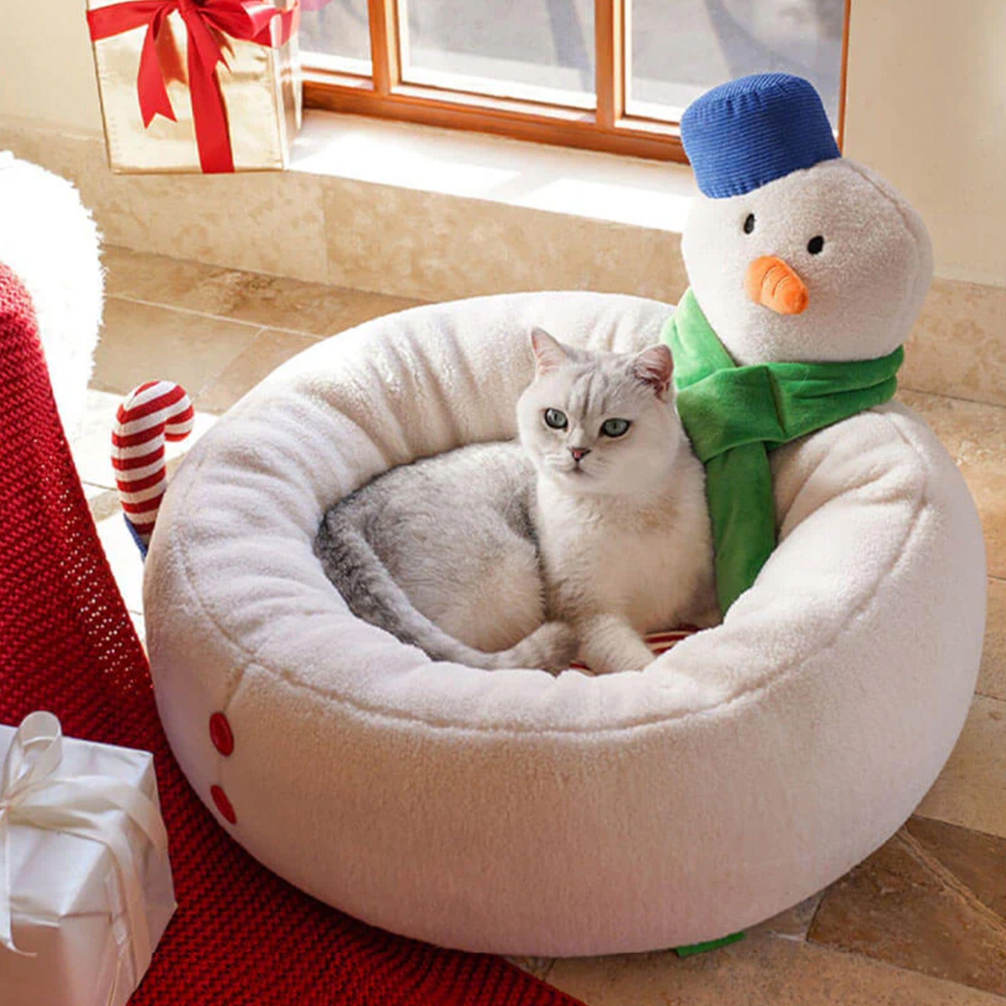 Katzenbett in Schneemann-Form, weiß, gemütlich, mit Katze, Weihnachtsdeko, Fensterhintergrund.