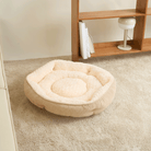 Beiges Cord-Samt-Haustierbett, rund, flauschig, auf Teppichboden vor Holzregal.