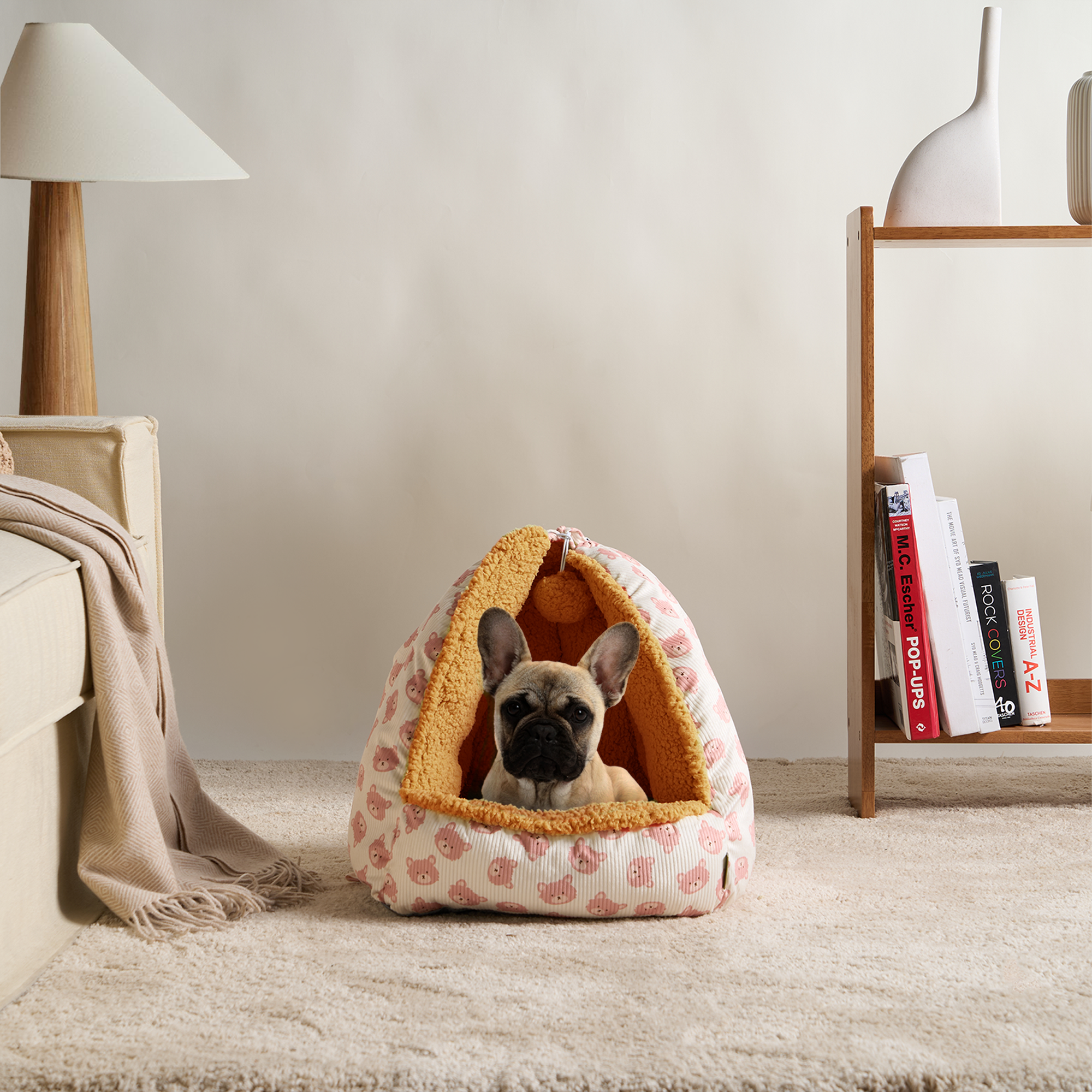 Französische Bulldogge in rosa Katzenhöhle aus Plüsch, gemütliches Haustierbett, Wohnzimmer.