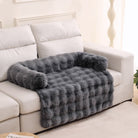 Graues, flauschiges Haustierbett auf weißem Sofa, gemütlich, weich, ideal für Hunde und Katzen.
