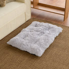 Graues, flauschiges Haustierbett auf Teppichboden neben Sofa, ideal für Hunde und Katzen.