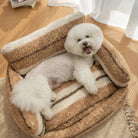 Weißer Hund auf braunem, plüschigem Haustier-Sofa, gemütliches Hundebett, Wohnzimmer.
