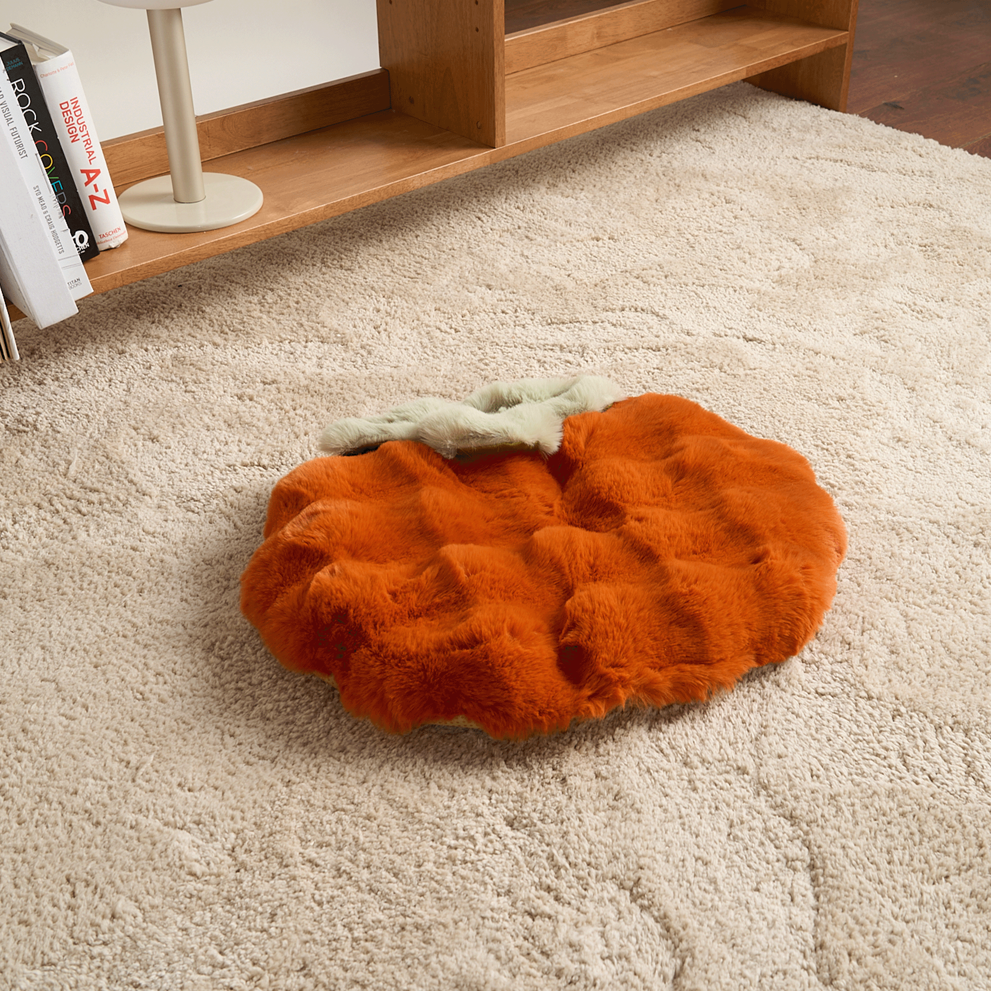 Orangefarbene, flauschige Schlafmatte auf beigem Teppich, modernes Design, gemütliche Wohnkultur.