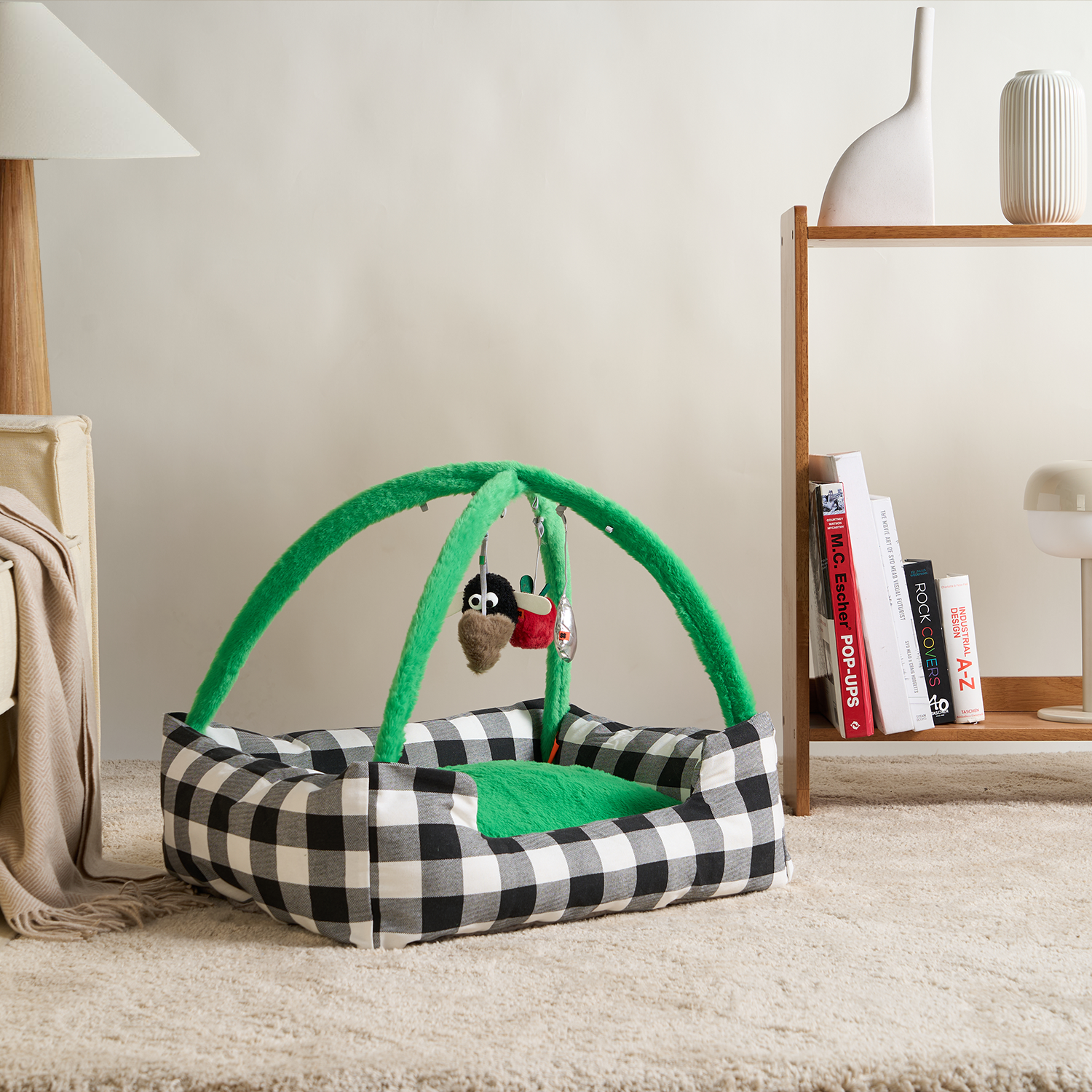 Schwarz-weiß kariertes Katzenbett mit grünem Spielbogen und hängendem Spielzeug.