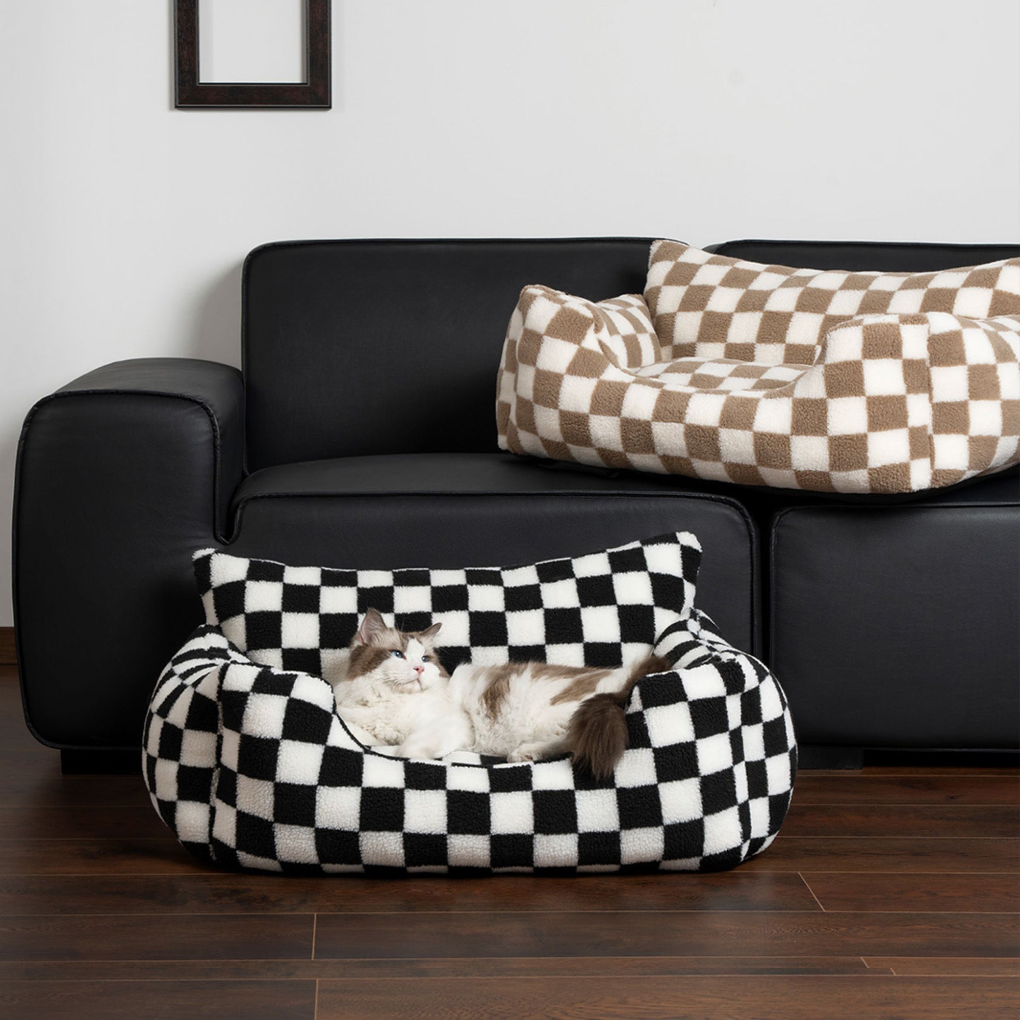 Schwarz-weiß kariertes Hundesofa, waschbar, auf schwarzem Ledersofa, modernes Design.