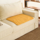 Gelbe, waffelgewebte, saugfähige Haustierunterlage auf beigem Sofa, ideal für Haustierpflege.
