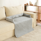 Wasserdichte graue Haustierdecke auf beigem Sofa, gesteppter Sofabezug, Wohnzimmer.