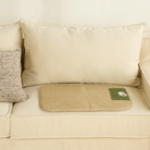 Geflochtete Rattan-Kühlmatte für Haustiere auf beigem Sofa, ideal für Sommerhitze.
