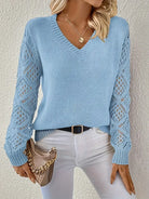 Damenpullover in Hellblau mit V-Ausschnitt und gehäkelten Ärmeln, kombiniert mit weißer Hose. Modischer Strickpullover für Herbst und Winter.