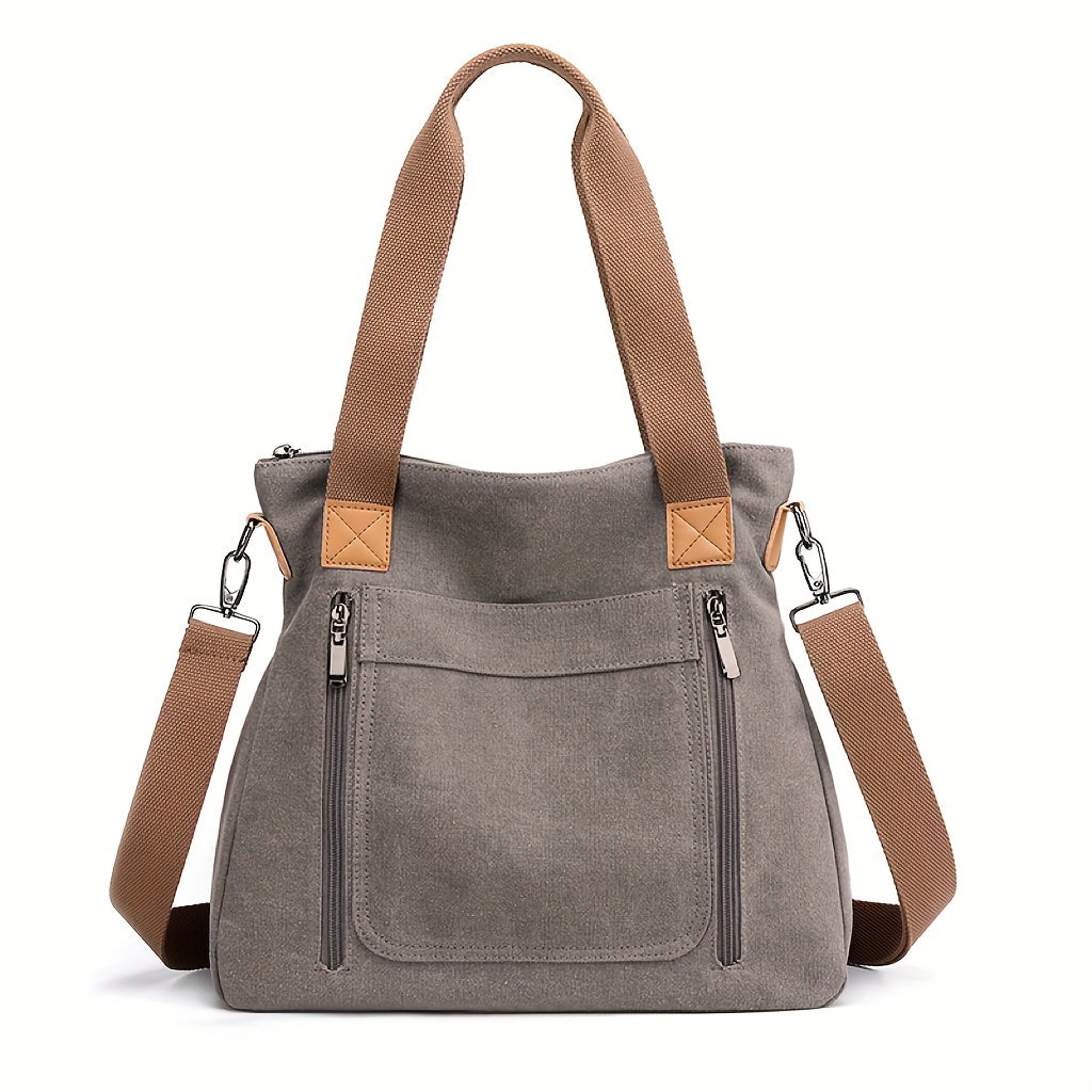 Stylische graue Canvas-Tasche mit braunen Trägern, Reißverschlusstaschen und abnehmbarem Schultergurt. Perfekt für Alltag und Reisen.