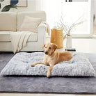 Gelber Labrador auf grauem, flauschigem Hundebett im Wohnzimmer, neben weißem Sofa.