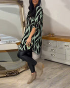 Damenmode: Stilvolle Tunika mit grün-schwarzem Muster, kombiniert mit schwarzer Leggings und beigen Stiefeletten. Perfekt für den modernen Look.