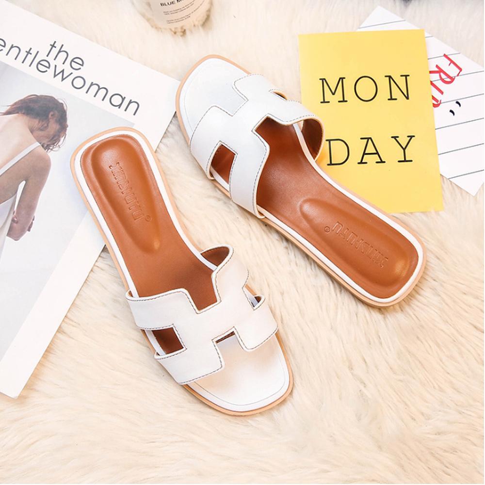 Weiße Damen-Sandalen auf flauschigem Teppich, modisch und bequem. Perfekt für den Sommer. Elegante Schuhe für Freizeit und Alltag.