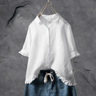 Weiße Damenbluse mit Rüschen, Baumwolle, lässig, elegant, auf Kleiderbügel vor grauem Hintergrund.