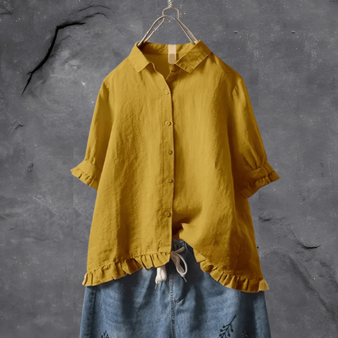 Gelbe Leinenbluse mit Rüschen, Damenmode, lässig, Sommer, hängend vor grauem Hintergrund.