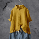 Gelbe Leinenbluse mit Rüschen, Damenmode, lässig, Sommer, hängend vor grauem Hintergrund.