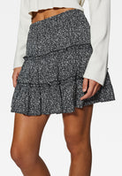 Schwarzer Minirock mit Blumenmuster, Rüschen und elastischem Bund. Perfekt für Sommermode, Damenbekleidung, trendige Outfits.