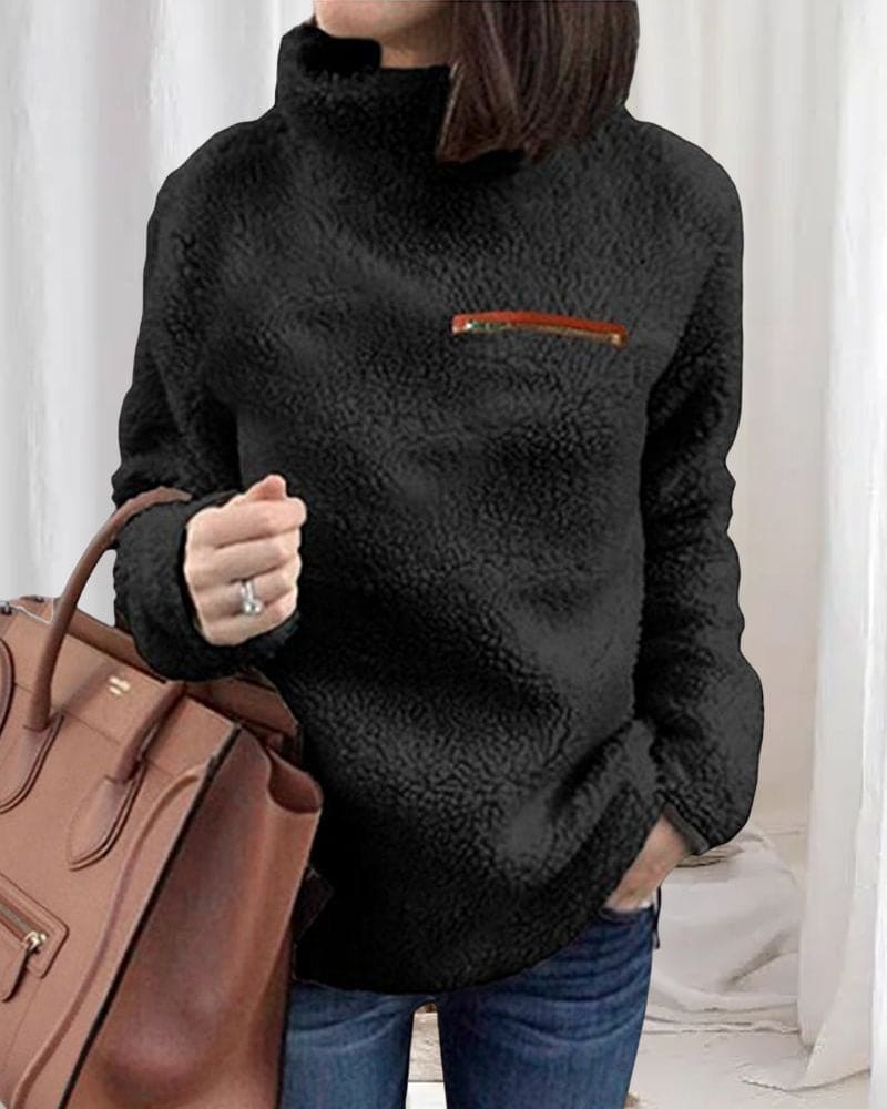 Damen-Fleece-Pullover in Schwarz mit hohem Kragen und Reißverschlusstasche, kombiniert mit brauner Lederhandtasche. Perfekt für Herbstmode.