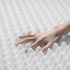 Hand drückt auf weiße, wellenförmige Schaumstoffmatratze, Komfort, Unterstützung, Textur.