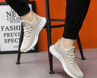 Beige Sneaker auf schwarzem Hocker, atmungsaktives Mesh, sportlich, modern, ideal für Laufen und Freizeit, modischer Schuhtrend 2023.
