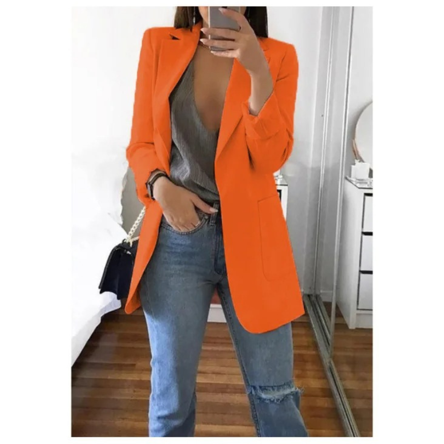 Frau in orangefarbenem Blazer, grauem Top und blauen Jeans. Modetrend, stilvolle Damenbekleidung, lässiger Look, Herbstmode.
