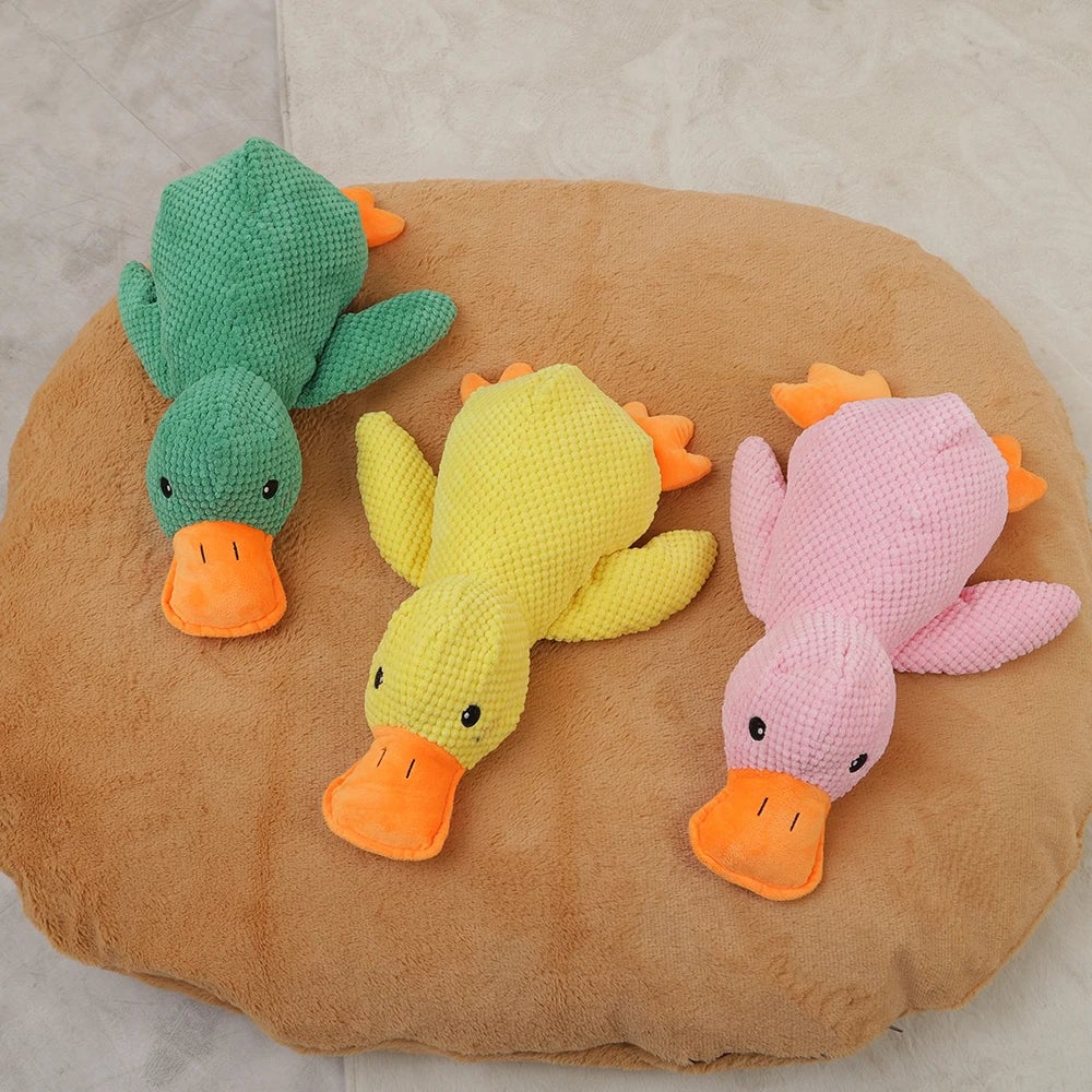 Drei Plüschenten in Grün, Gelb und Rosa auf einem braunen Kissen. Kuscheltier, Kinderzimmer-Deko, Geschenkidee, weiches Spielzeug.