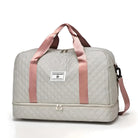 Graue Reisetasche mit rosa Trägern, gestepptem Design, Reißverschluss und Markenlogo.