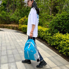 Frau mit blauem Rucksack, weißem T-Shirt und schwarzer Hose spaziert im Park.