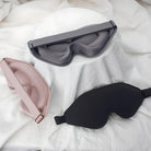 Drei ergonomische Schlafmasken in Schwarz, Grau und Rosa auf weißem Hintergrund.