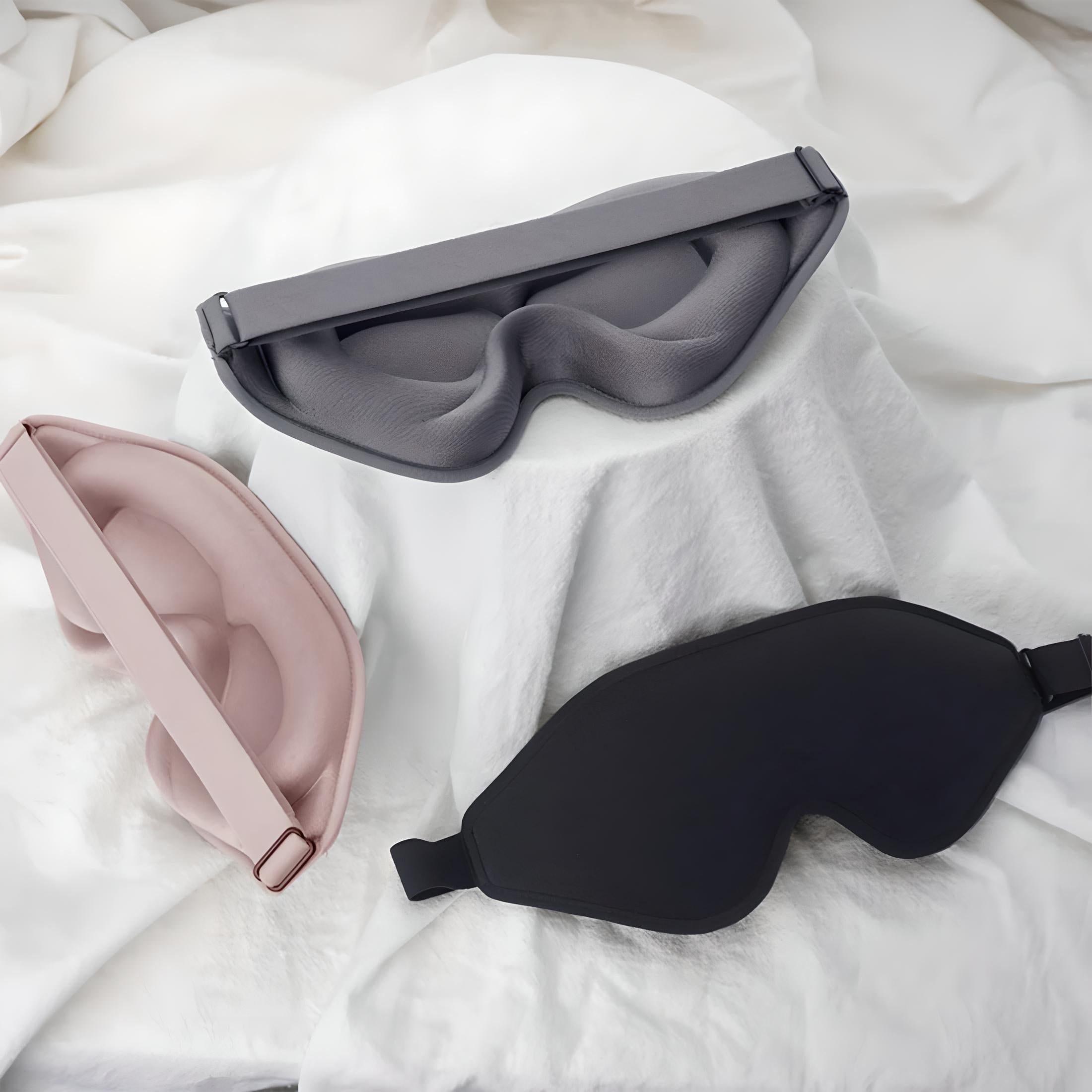 Drei ergonomische Schlafmasken in Schwarz, Grau und Rosa auf weißem Hintergrund.