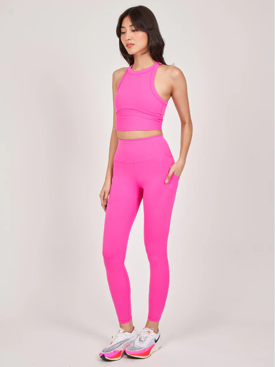 Frau in pinkem Sport-Set, bestehend aus Leggings und Crop-Top, ideal für Fitness und Yoga. Trendige Sportmode, bequem und stylisch.