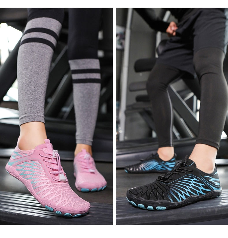 Zwei Paar Barfußschuhe auf Laufband: Rosa Damenmodell und schwarzes Herrenmodell. Ideal für Fitness, Laufen und Sport. Leicht und atmungsaktiv.