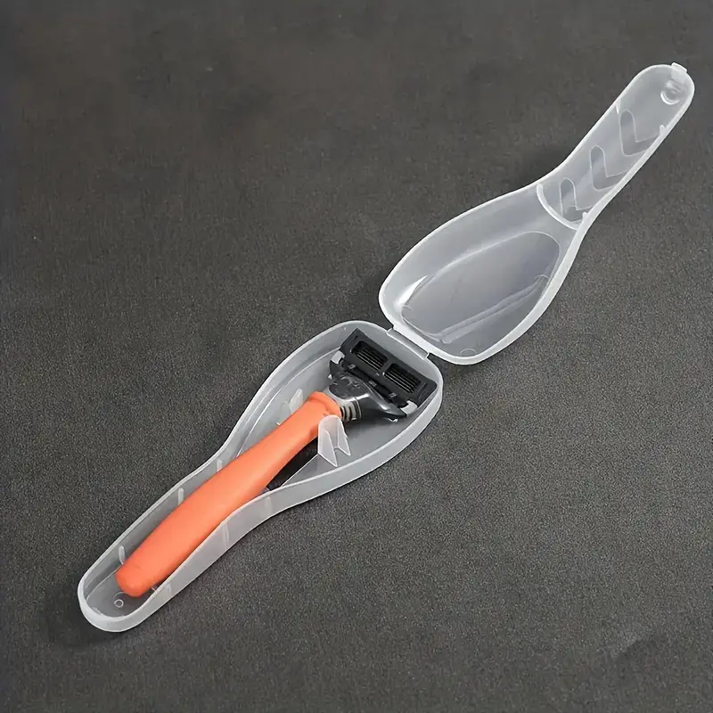 Rasierer mit orangefarbenem Griff in transparenter Kunststoffhülle auf grauem Hintergrund.