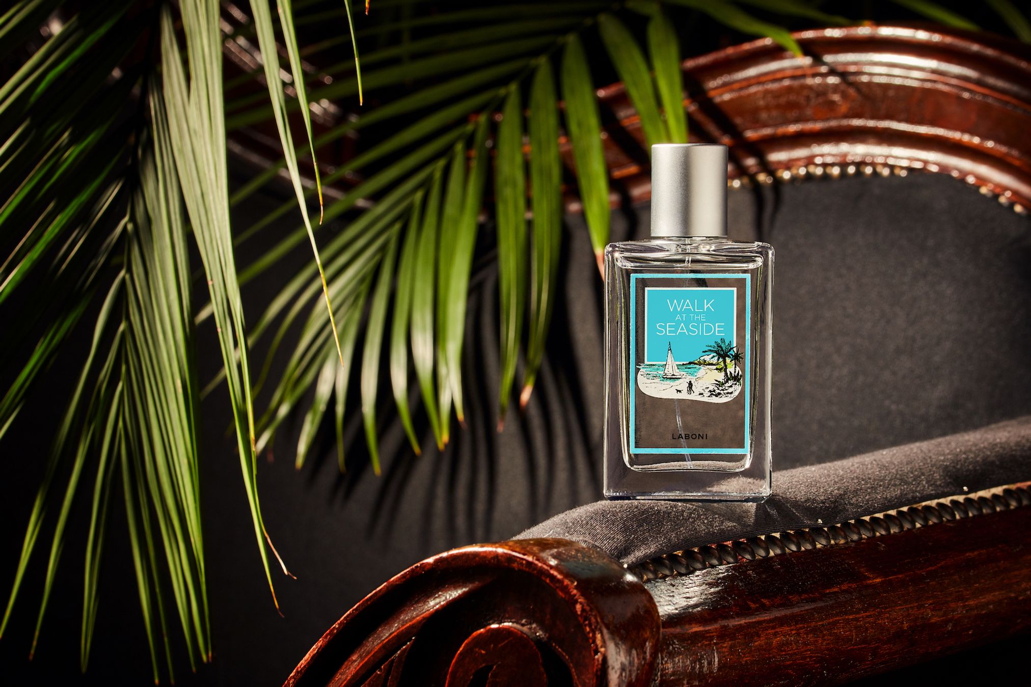 Parfümflasche "Walk Seaside" auf Holzstuhl, tropische Blätter, luxuriöses Design.