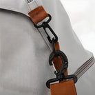 Grauer Rucksack mit braunem Gurtband und schwarzem Karabinerhaken, robustes Design.