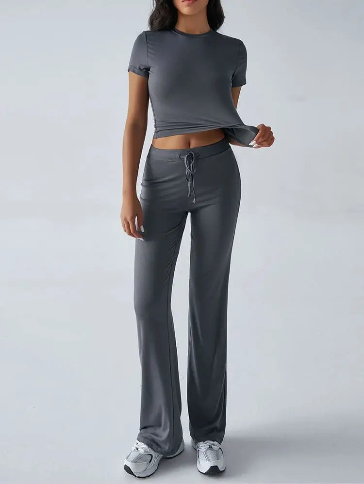 Damen-Sportanzug in Grau, bestehend aus kurzärmligem Oberteil und Jogginghose. Ideal für Fitness, Yoga und Freizeit. Bequem und stilvoll.