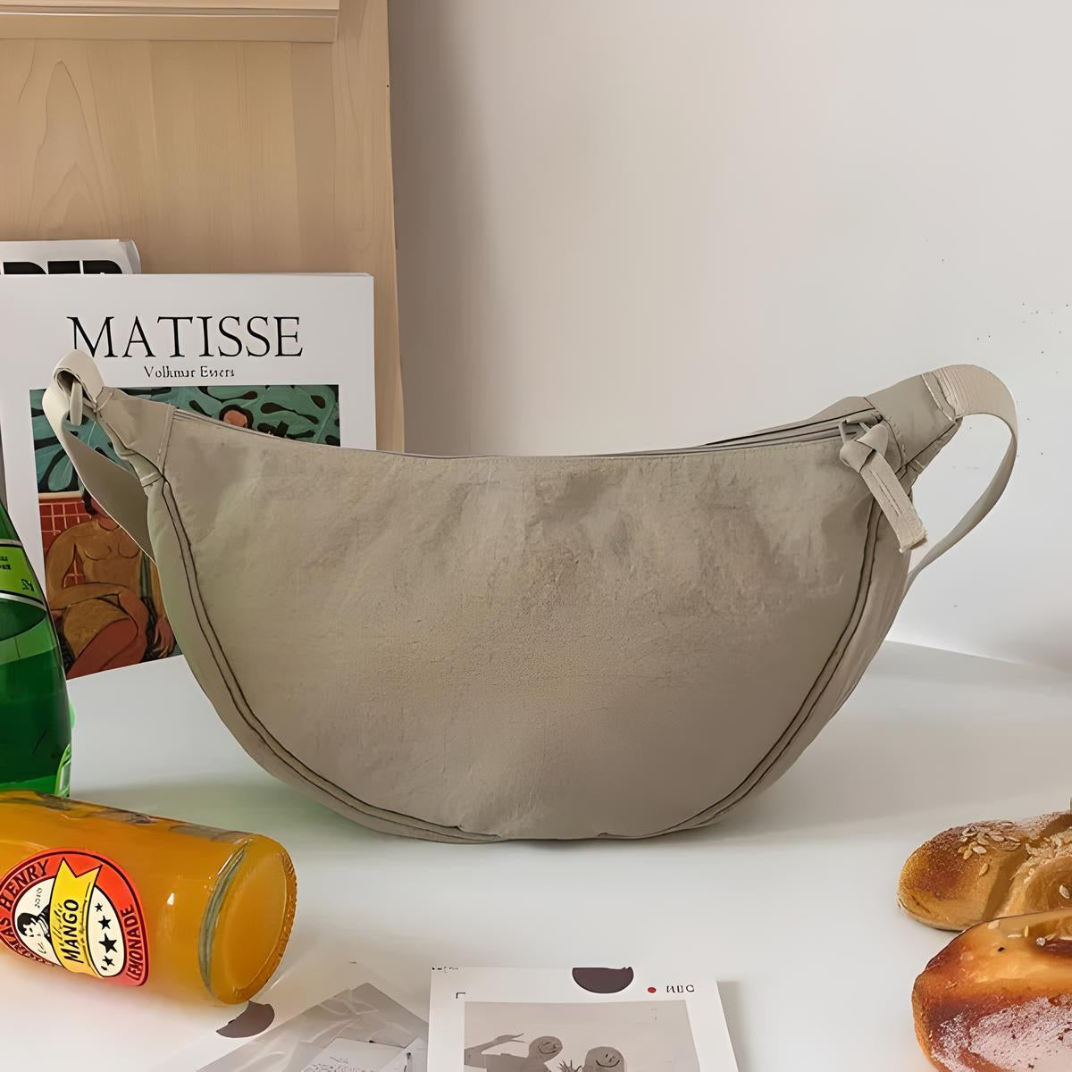 Beige Umhängetasche aus Segeltuch, modisch, praktisch, ideal für den Alltag, neben Getränken und Brot.