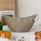 Beige Umhängetasche aus Segeltuch, modisch, praktisch, ideal für den Alltag, neben Getränken und Brot.