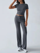 Damen-Sportanzug in Grau, bestehend aus kurzärmeligem Crop-Top und weiten Hosen. Ideal für Fitness, Yoga und Freizeit. Bequem und stilvoll.