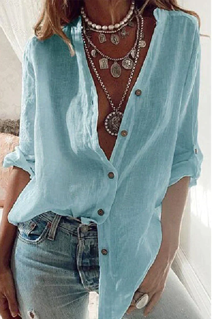 Damenmode: Hellblaue Leinenbluse, lässig geknöpft, kombiniert mit Jeans und auffälligen Halsketten. Perfekt für Sommer und Freizeit.