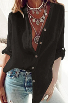 Elegante schwarze Bluse, lässig geknöpft, kombiniert mit modischen Jeans und auffälligen Halsketten. Perfekt für trendige Damenmode.
